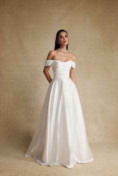 a woman in a white wedding dress posing for the camera with her hands on her hips