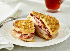 a waffle sandwich cut in half on a plate next to a cup of tea