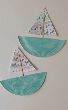 two paper plates with boats on them and some sticks sticking out of the top one