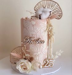 a pink cake with white flowers on top and the number twenty five in gold lettering