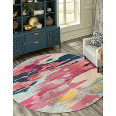 a colorful rug in a living room next to a chair and bookcase with books on it