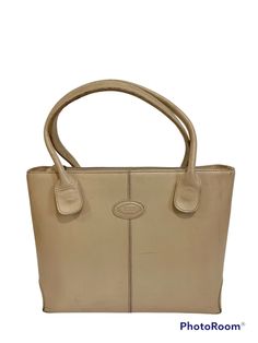 Central ribbing and tubular handles characterize this elegant shopping bag with Tod's logo stamped on the front. Crafted in calfskin leather, it features an internal pouch. To accompany everyday outfits with class and femininity. Made in Italy Women's Tod's Di Bag Shopping Bag in beige Item crafted in leather Tod's logo stamped on the front Zip closure Internal zipped pouch Metal feet Dimensions: 13.8 x 10 x 5.1 ins, fixed handles 7.25 ins One Interior pocket In fair vintage condition, has many Classic Cream Bags With Rolled Handles, Formal Beige Bags With Rolled Handles, Formal Beige Shoulder Bag With Rolled Handles, Classic Beige Bags With Rolled Handles, Classic Shoulder Bag With Rolled Handles For Shopping, Classic Cream Shoulder Bag For Shopping, Classic Rectangular Shoulder Bag With Rolled Handles, Classic Tan Shoulder Bag For Shopping, Yarn Bag