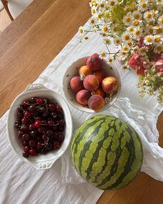 three bowls filled with fruit sitting on top of a table next to a bowl of cherries