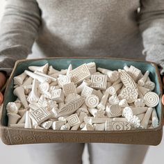 a person holding a tray full of ceramic objects