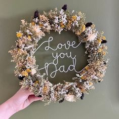 a hand holding a wreath with the words i love you dad written on it