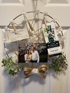 a family photo hanging on the front door with flowers and ribbons attached to it's frame