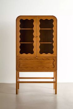 an old wooden cabinet with glass doors on the front and bottom, against a white wall