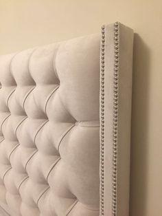 an upholstered white headboard with beading on the top and bottom part