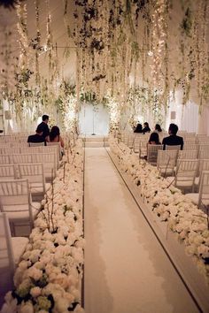 the aisle is decorated with white flowers and greenery