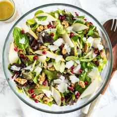 a salad with apples, walnuts and pomegranate in a glass bowl