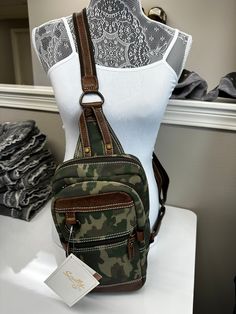 a green camo purse on display in front of a white mannequin