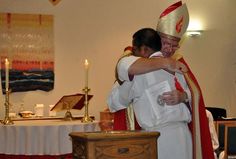 two people hugging each other in front of a table