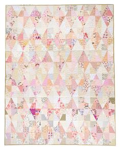 a pink and white quilt with lots of small triangles on the front, in pastel colors