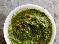 a white bowl filled with pesto on top of a table