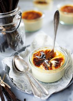 small desserts with spoons are sitting on a plate next to glass jars and spoons