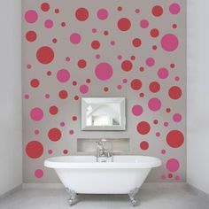 a bath tub sitting under a bathroom mirror next to a wall with dots on it