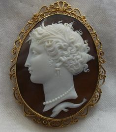 a white and brown brooch with a woman's head on it