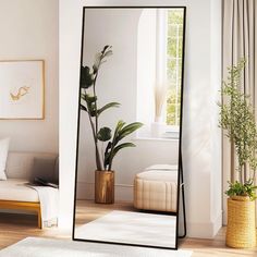 a large mirror sitting on top of a wooden floor next to a plant in a vase