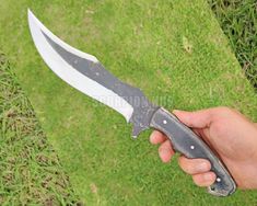 a person holding a knife in their hand on the grass with it's blade out