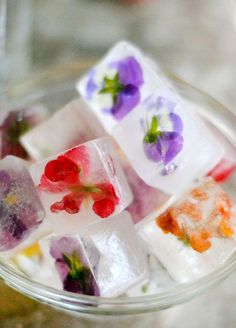 four different types of ice cubes with flowers on them in a glass bowl,