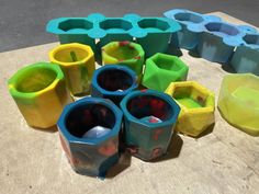 several different colored cups sitting on top of a wooden table next to some plastic containers