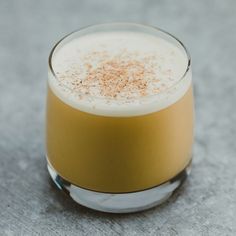 a close up of a drink in a glass on a table with a gray background