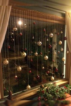 a window with christmas ornaments hanging from it's side and curtains on the outside