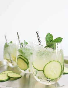 three glasses filled with cucumber and mintade on a metal serving platter