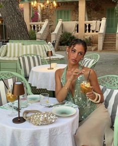 a woman sitting at an outdoor table with food and drinks in front of her,