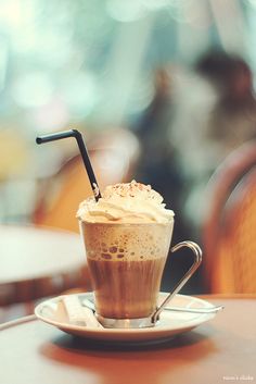 a cup of coffee with whipped cream and a straw in it on a saucer