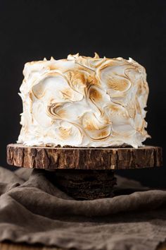 a white frosted cake sitting on top of a wooden plate