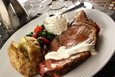 a white plate topped with meat, potatoes and veggies next to a pastry