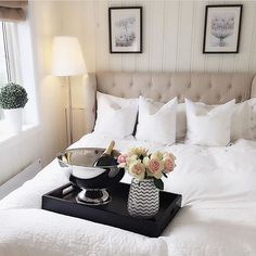 a tray with flowers on top of a bed next to a vase filled with roses