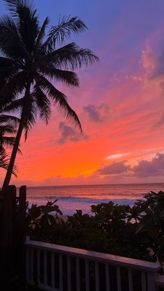 the sun is setting over the ocean with palm trees in front of it and an ocean view