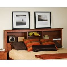 a bed with two pictures above it and pillows on the bottom shelf next to it