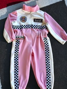 a pink and white racing suit laying on the ground