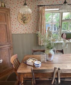 a wooden table sitting in front of a window next to a vase with flowers on it