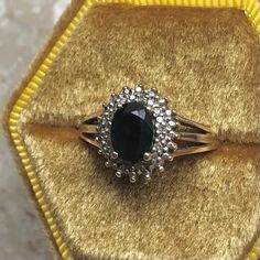 a black diamond ring sitting on top of a yellow velvet box with gold trimming