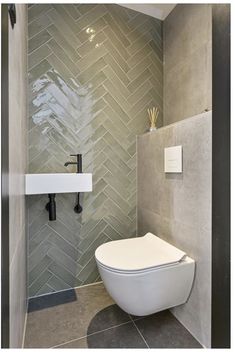 a white toilet sitting inside of a bathroom next to a wall mounted faucet