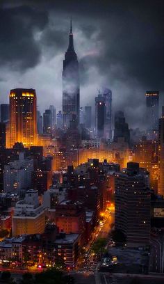 the city skyline is lit up at night, with dark clouds in the sky above