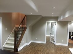 an empty living room with stairs leading up to the second floor and another open door