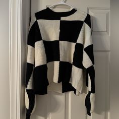 a black and white sweater hanging on a door