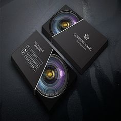 two black business cards with an image of a camera on it and the bottom one has a yellow lens