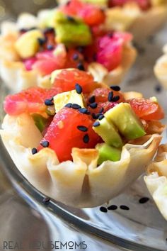 small cups filled with fruit on top of a metal tray and topped with black seeds