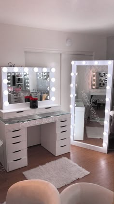 a white vanity with lighted mirrors and stool