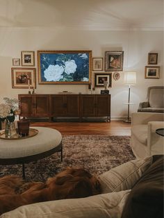 a living room filled with furniture and pictures on the wall next to a coffee table