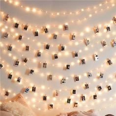 a bedroom with lights strung from the ceiling and pictures hung on the wall above it