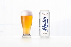 a can of beer next to a glass on a table