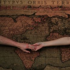 two people holding hands over a world map