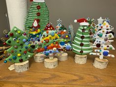 there are many small christmas trees on the table and one is made out of wood